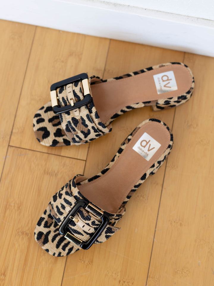 Leopard print sandals with a buckle on a wooden floor