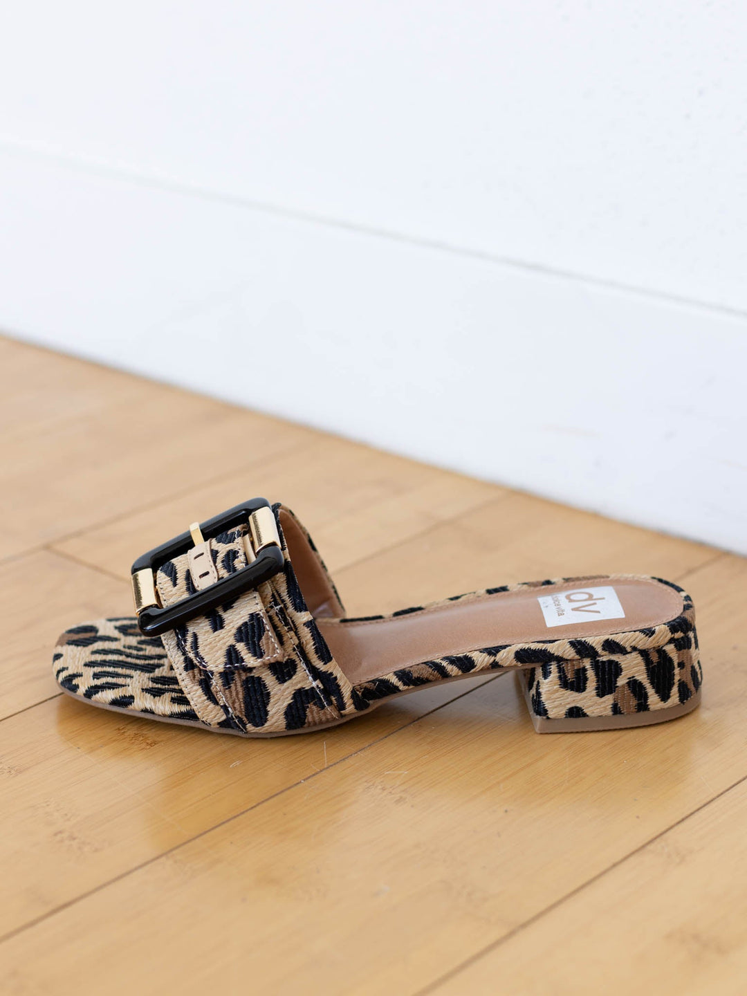Leopard print sandals with a buckle on a wooden floor