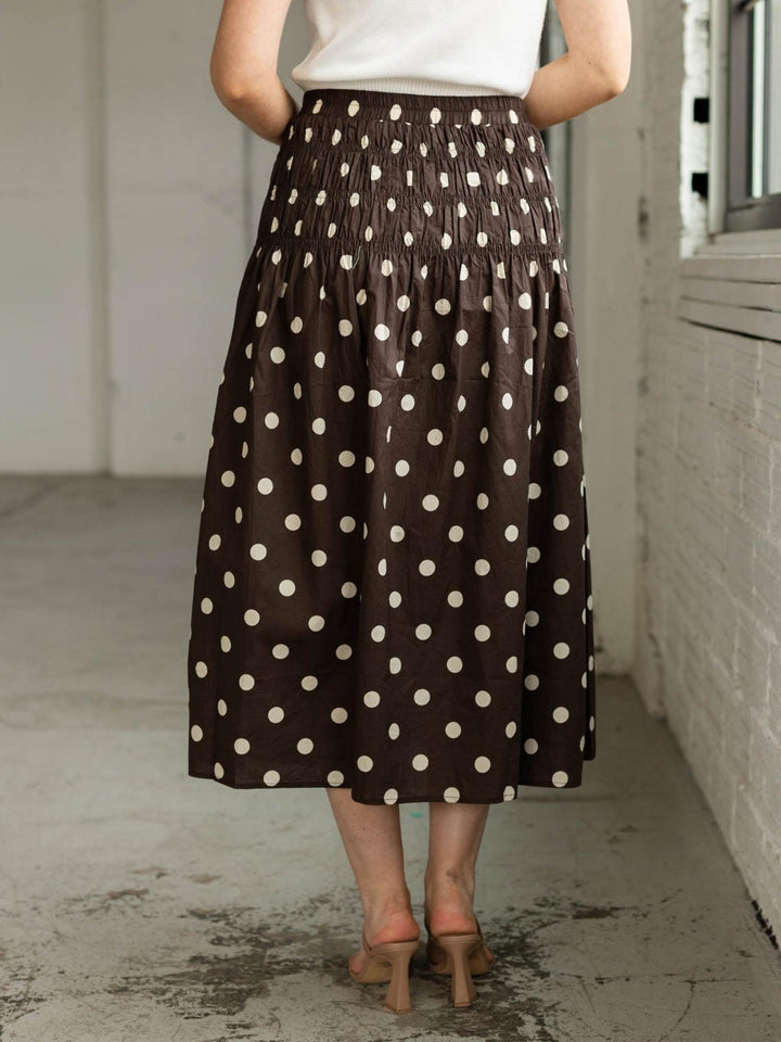 Person wearing a brown polka dot skirt in an indoor setting