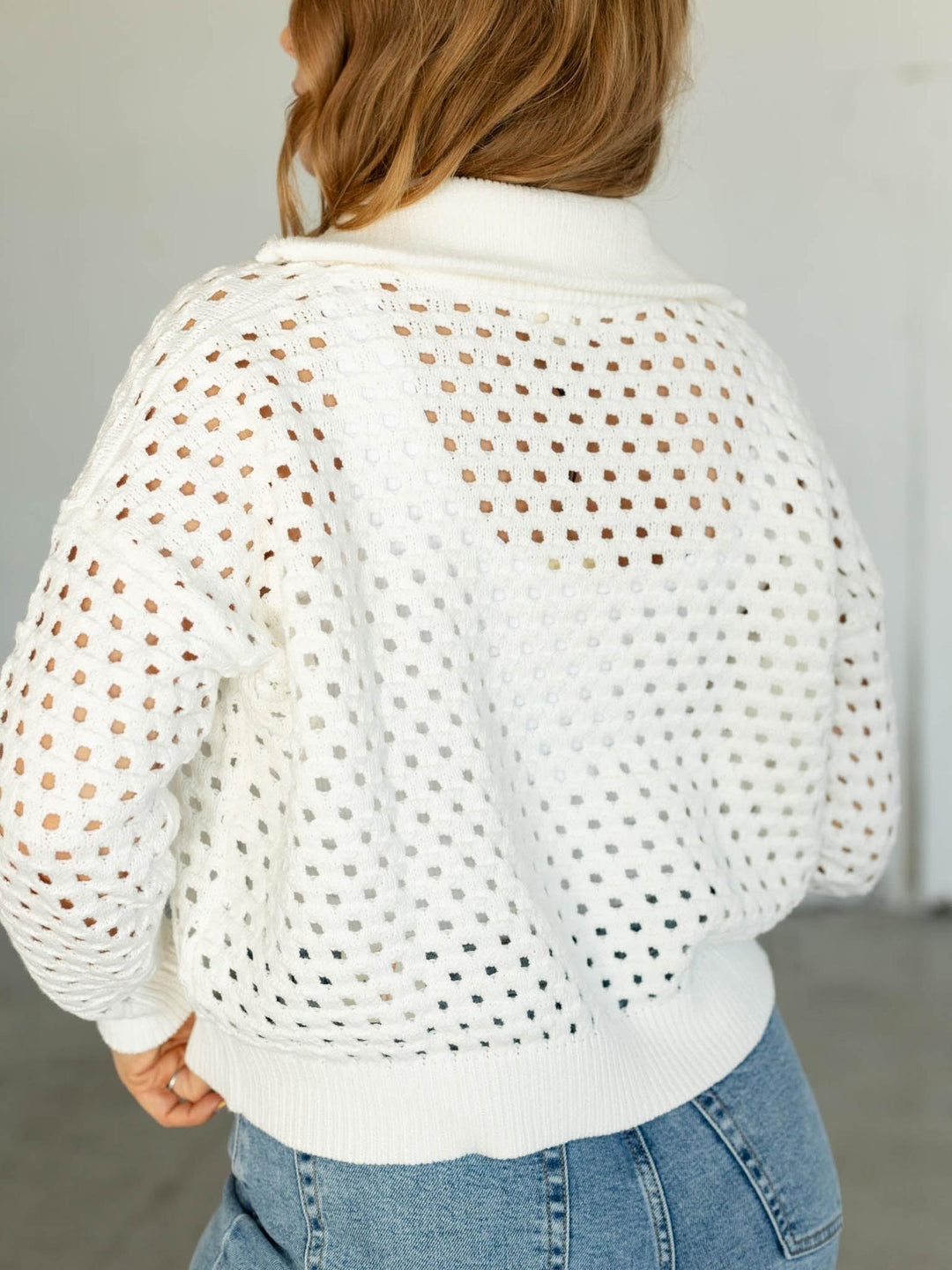 Person wearing a white perforated jacket with a blurred background