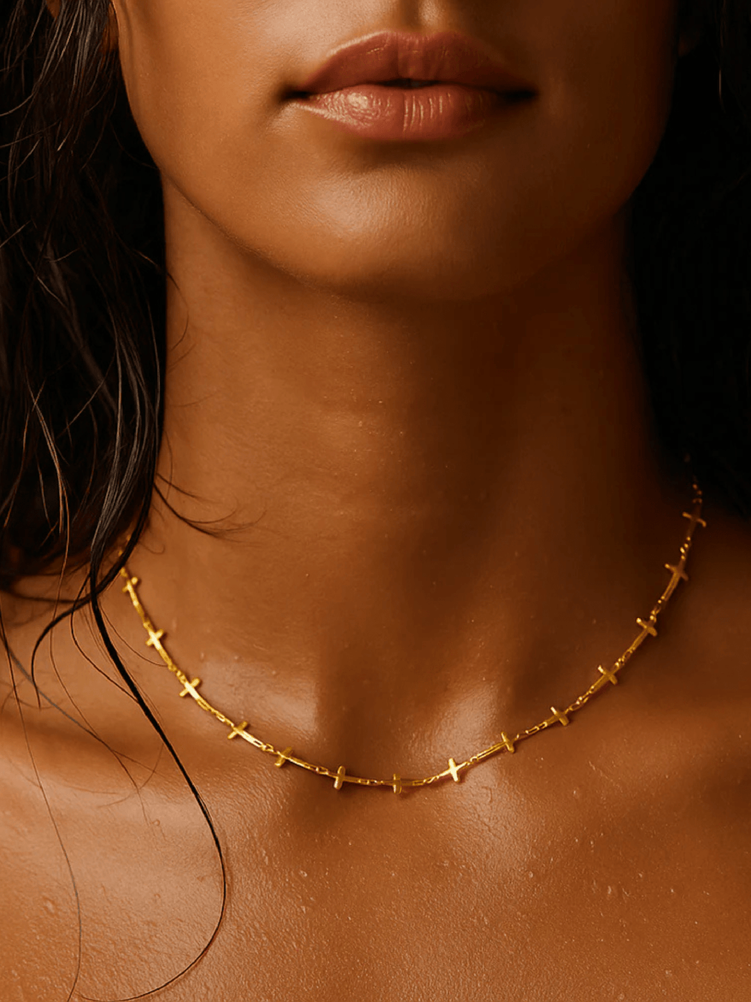 Close-up of a person wearing a gold necklace with a dark background