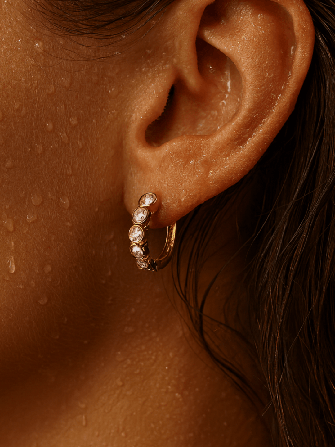 Close-up of an ear wearing a gold hoop earring with pearls.