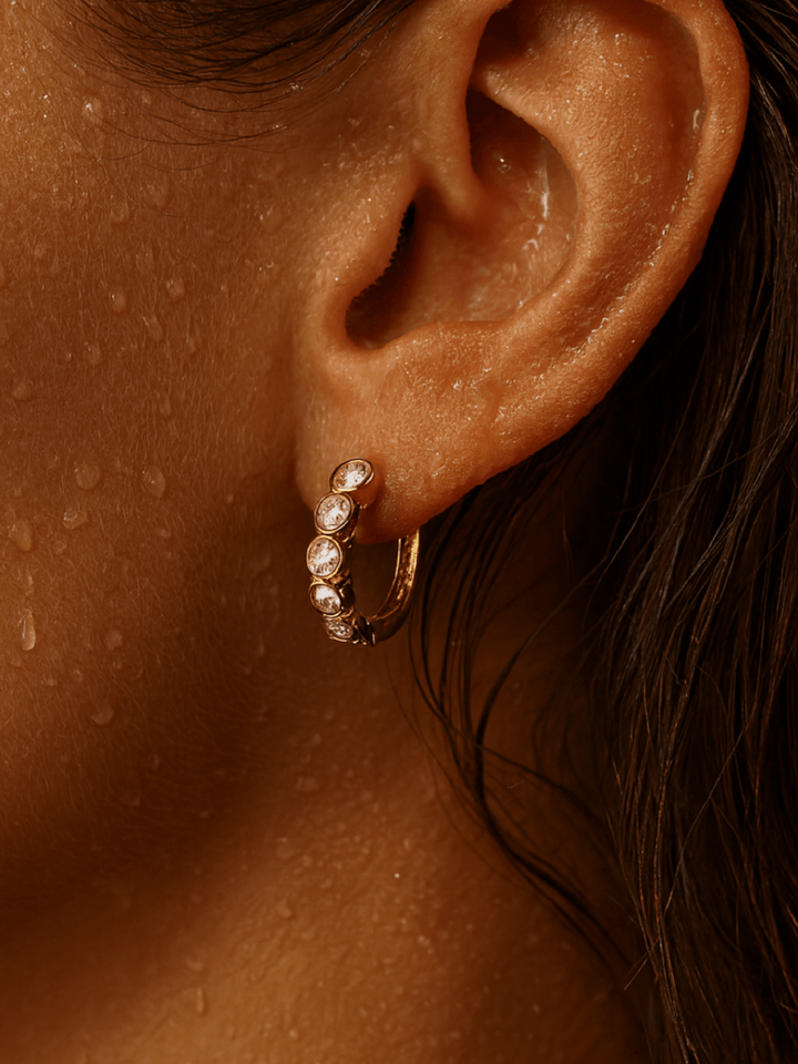 Close-up of an ear wearing a gold hoop earring with pearls.