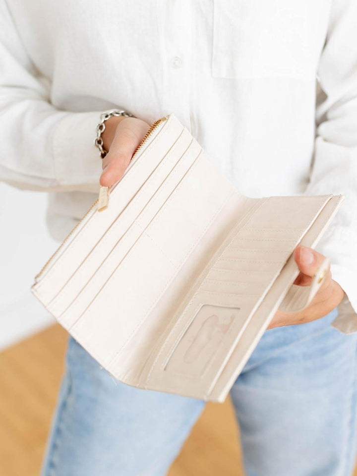 Person holding a beige wallet with a blurred background