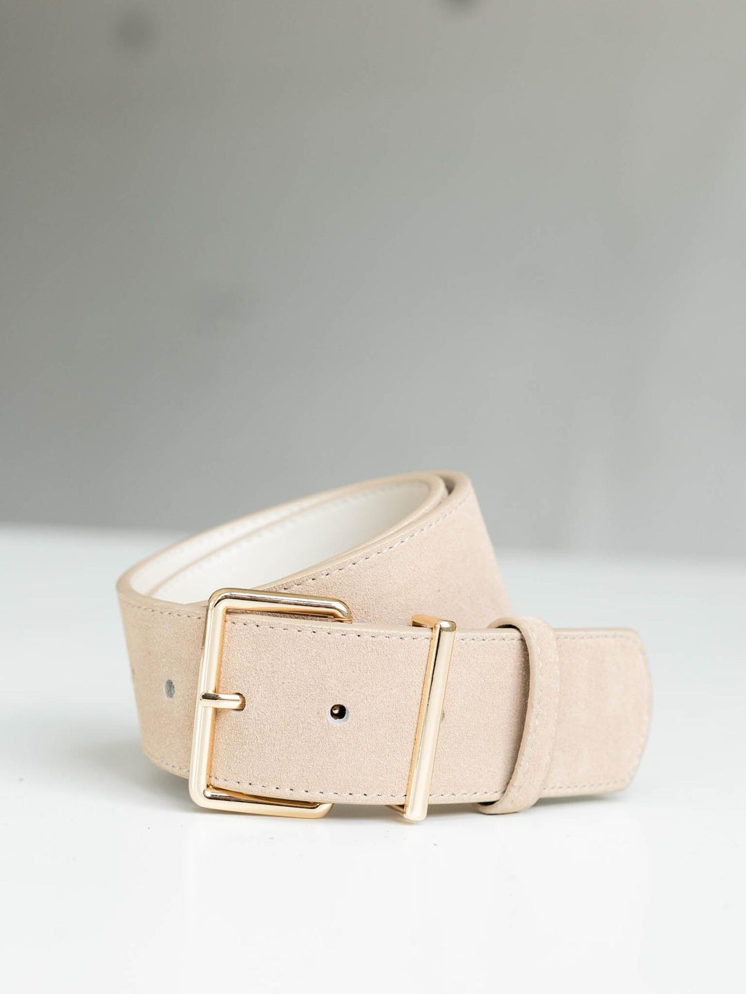 Almond suede belt with a modern angular gold buckle and streamlined silhouette.