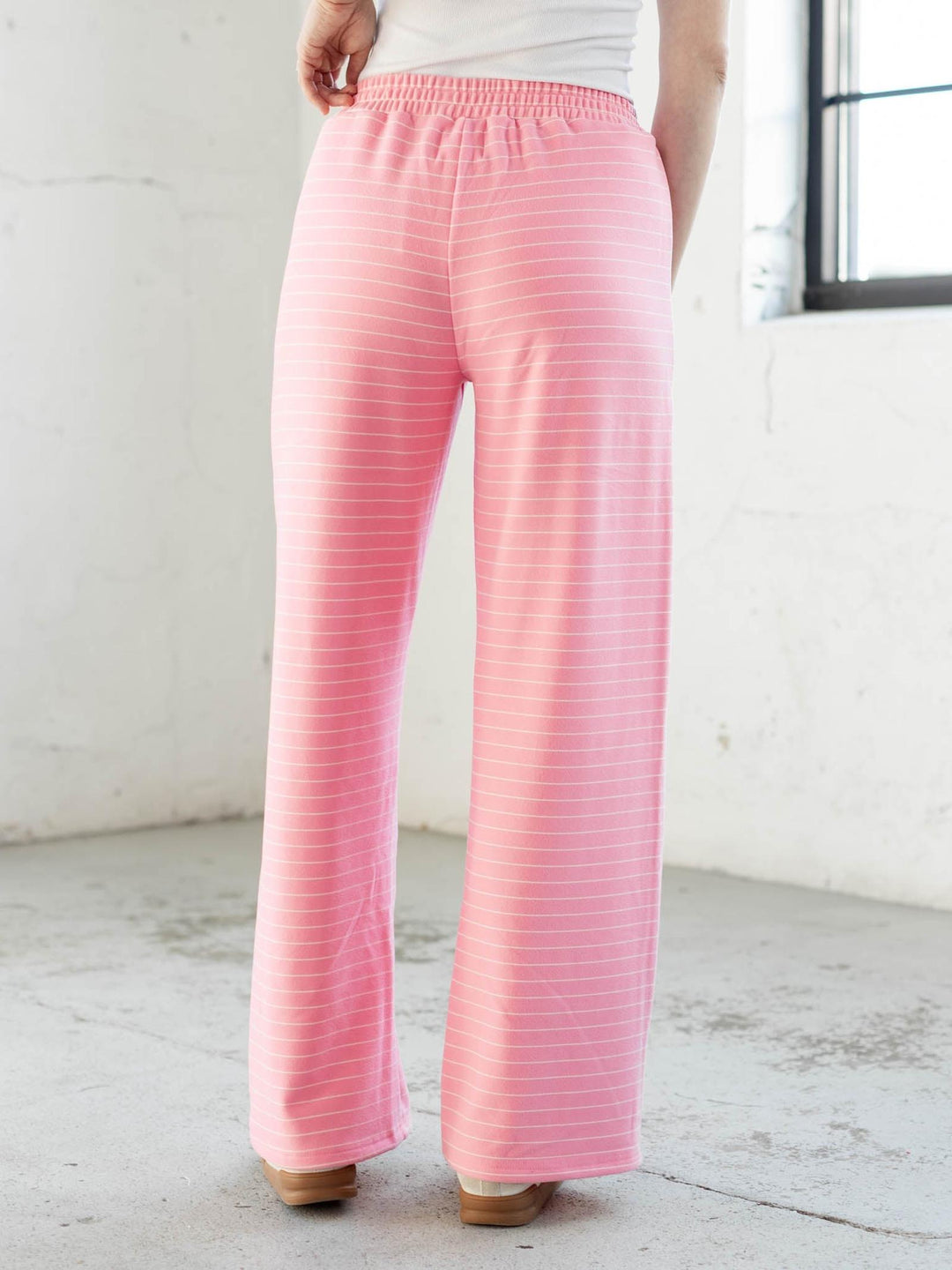 Person wearing pink striped pants in a minimal indoor setting
