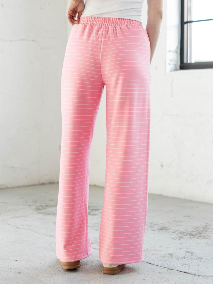Person wearing pink striped pants in a minimal indoor setting