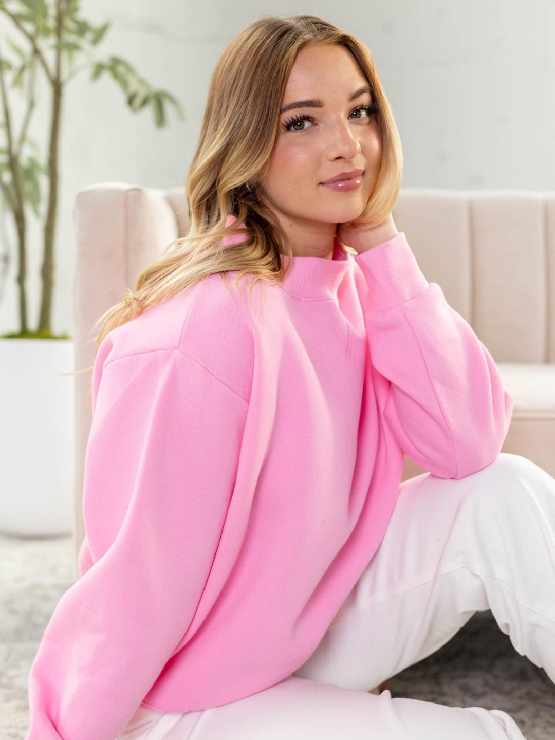 Woman wearing a pink blanket in a cozy living room setting