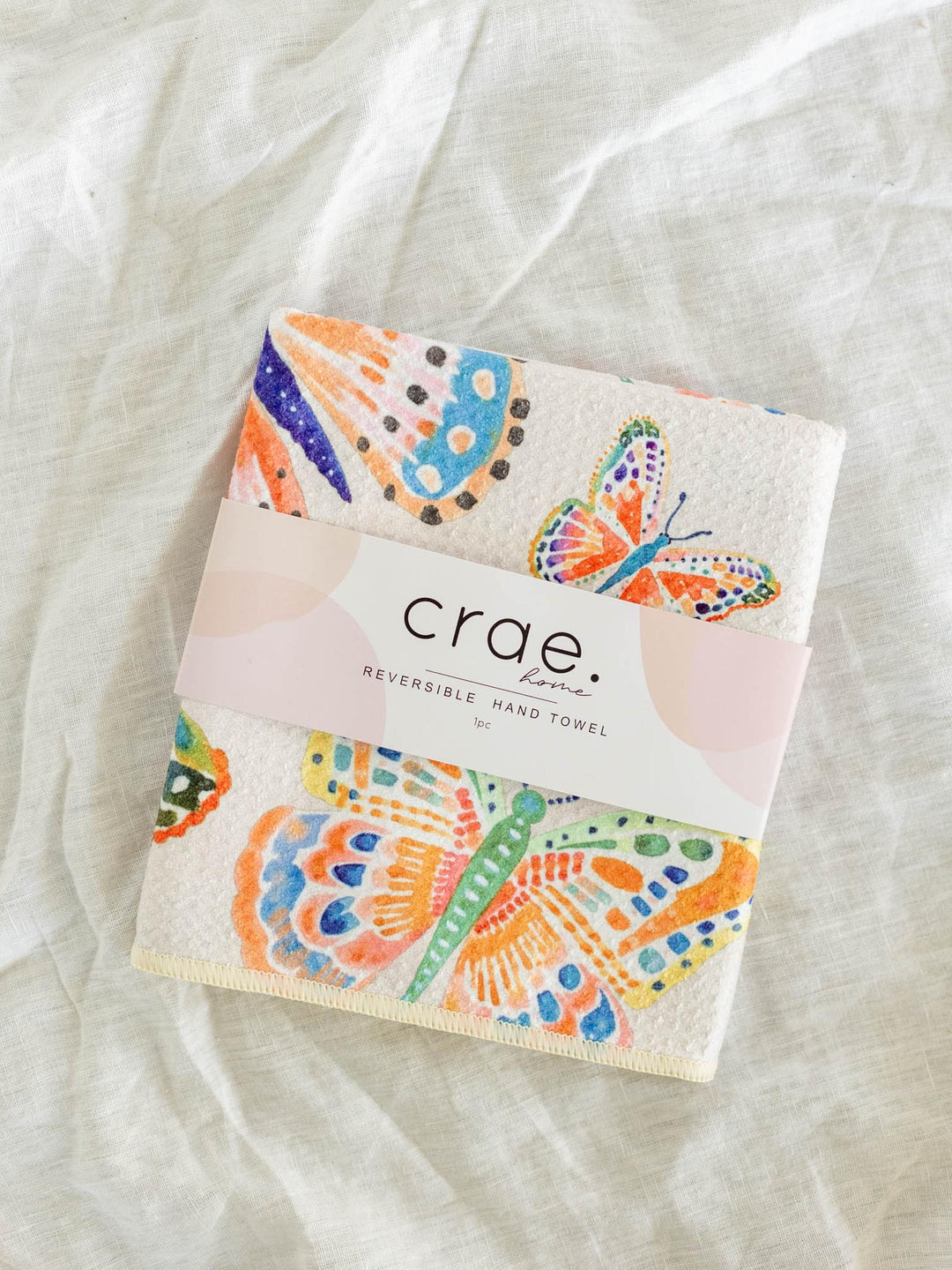 Packaged reversible hand towel with colorful butterfly design on a light fabric background
