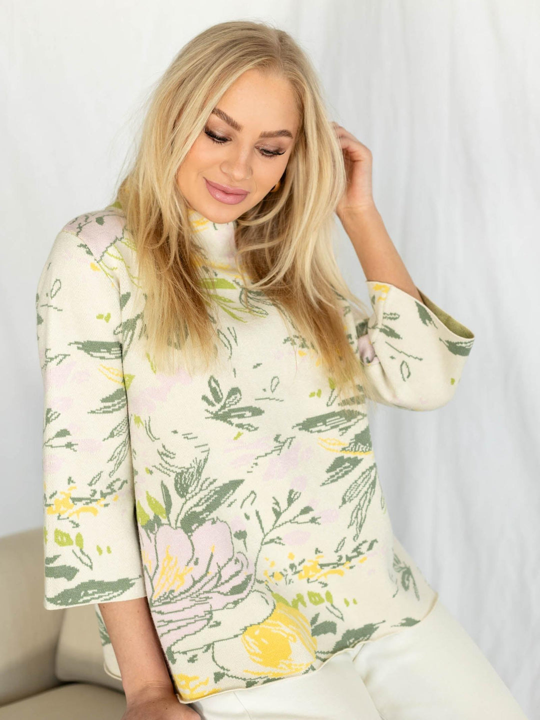 Woman wearing a floral-patterned sweater against a white background