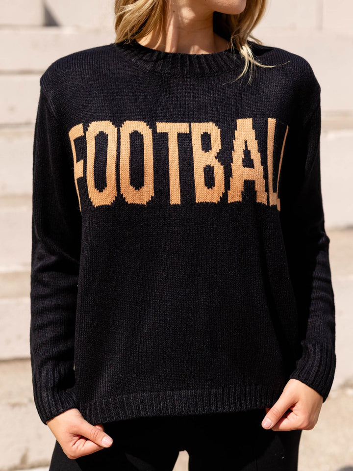 A woman wearing a black knit sweater with the word &
