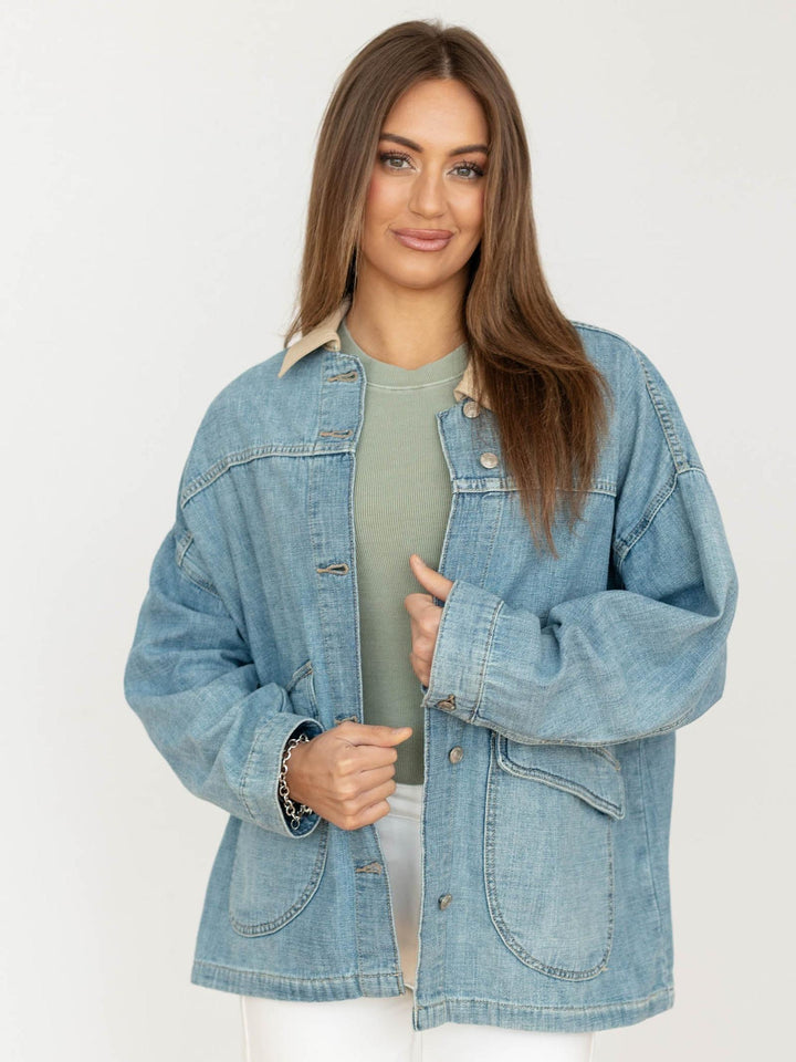 Woman wearing a blue denim jacket over a green shirt on a white background