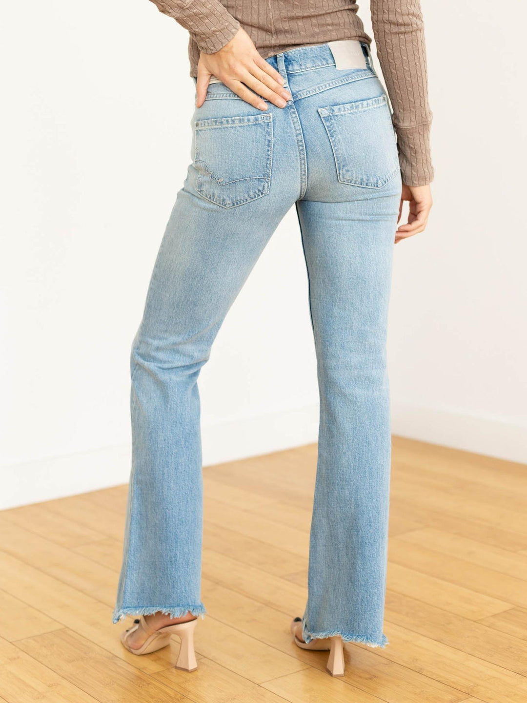 Light blue flared jeans worn by a person on a wooden floor.