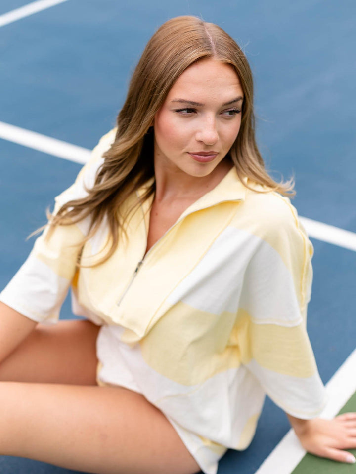 Woman in a Free People Retro Rugby Set, featuring a yellow and white striped 100% cotton top with a zipper.