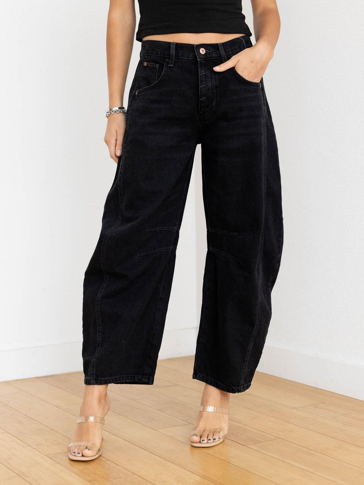 Person wearing black wide-leg jeans and a black top on a white background