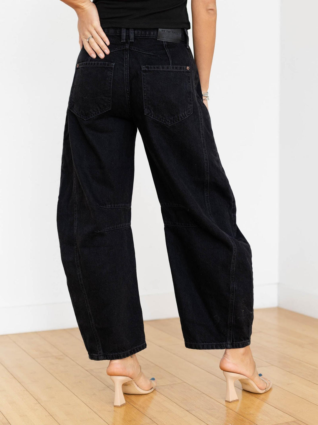 Person wearing black wide-leg jeans on a plain background