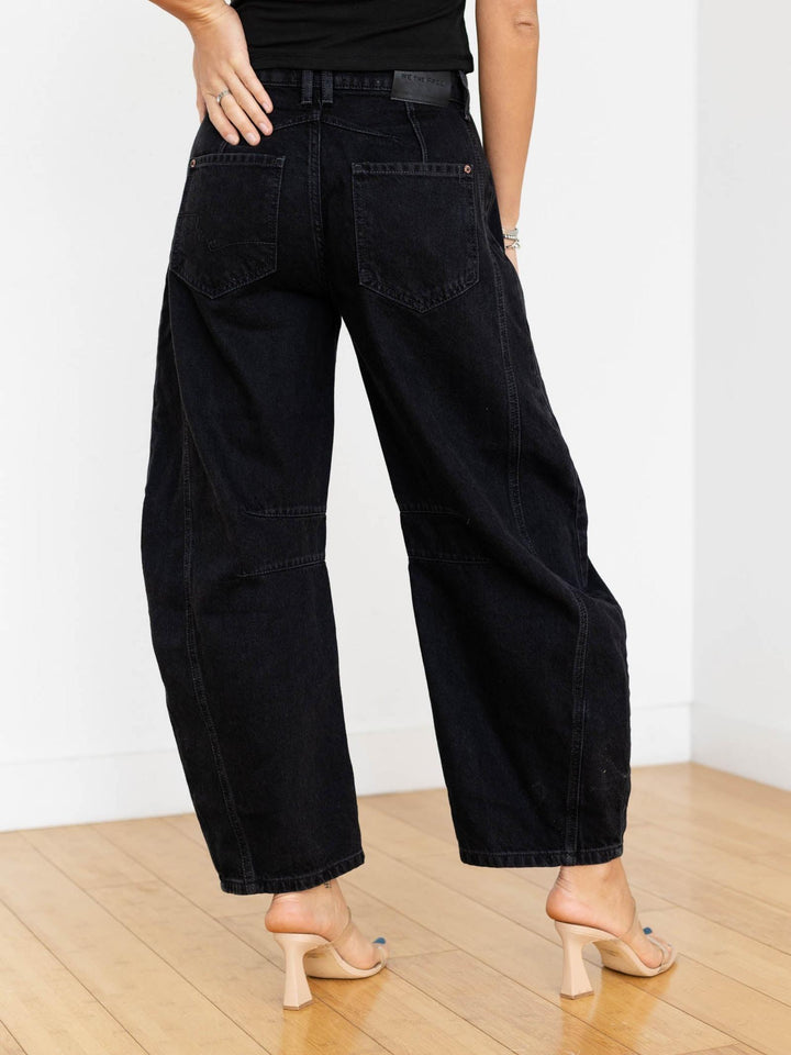 Person wearing black wide-leg jeans on a plain background