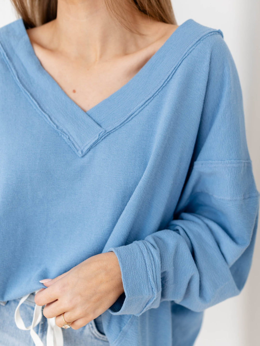 Woman wearing a blue oversized sweater and denim shorts against a white background
