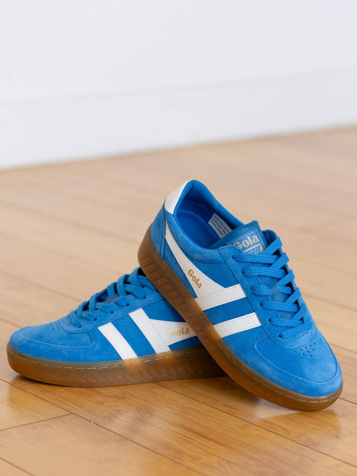 Blue sneakers with white stripes on a wooden floor