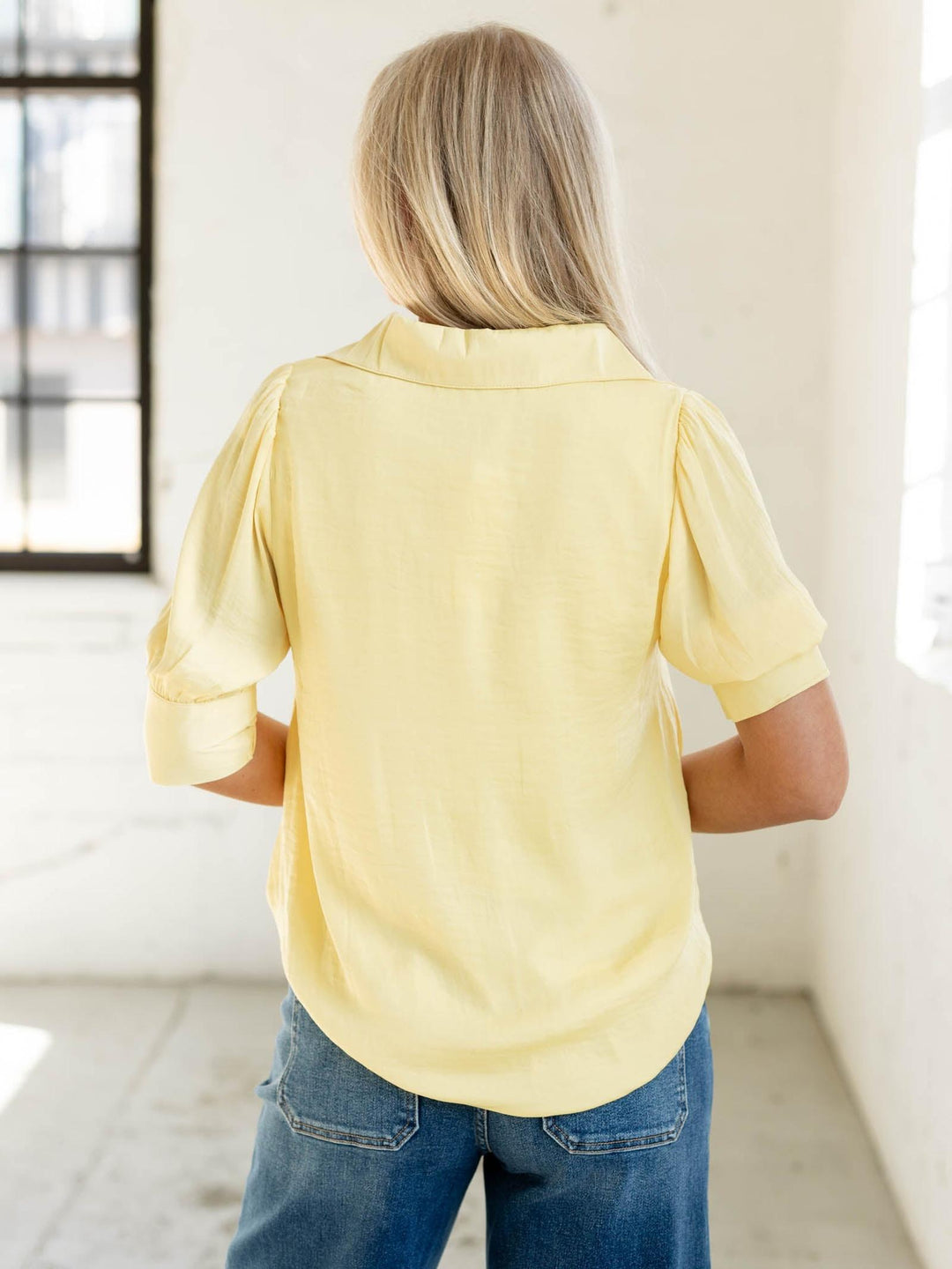Person wearing a yellow shirt and blue jeans in a bright room