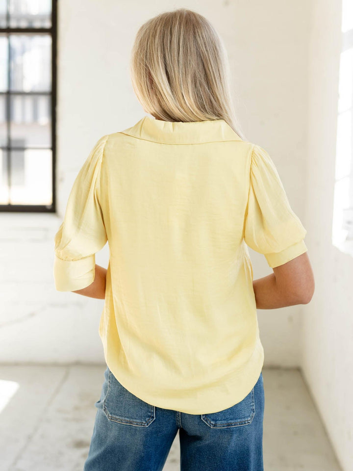 Person wearing a yellow shirt and blue jeans in a bright room