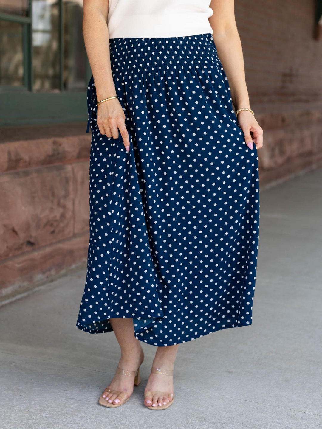 Person wearing a navy blue skirt with white polka dots outdoors.