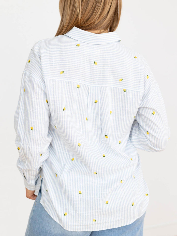 White shirt with yellow polka dots worn by a person on a white background