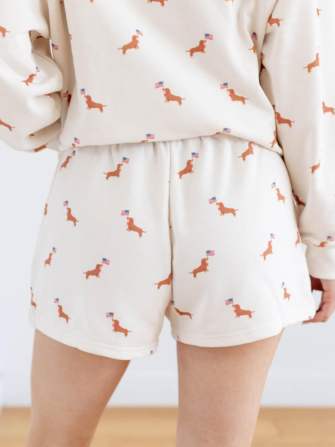Person wearing a cream-colored outfit with dachshund pattern on a plain background