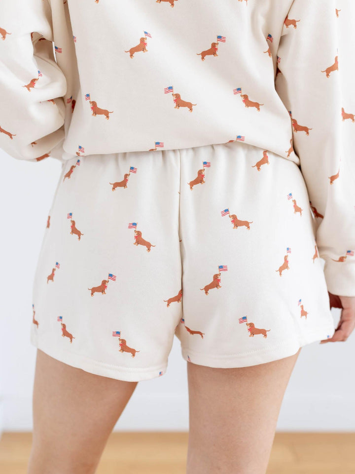 Person wearing a cream-colored outfit with dachshund pattern on a plain background