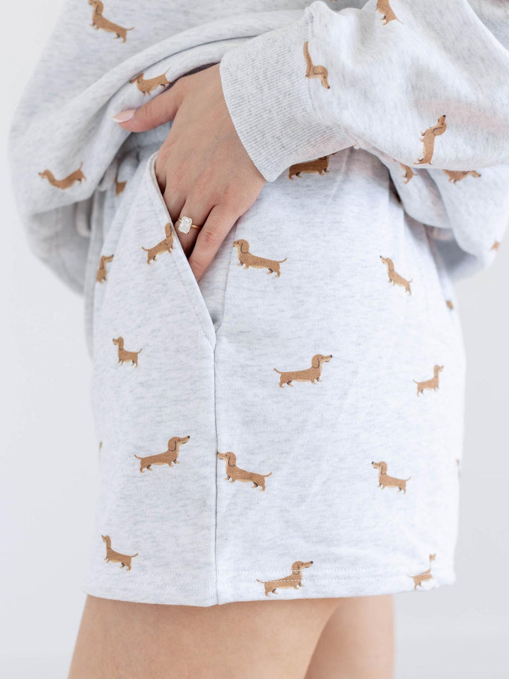 Light gray hoodie with brown dachshund pattern worn by a person on a white background