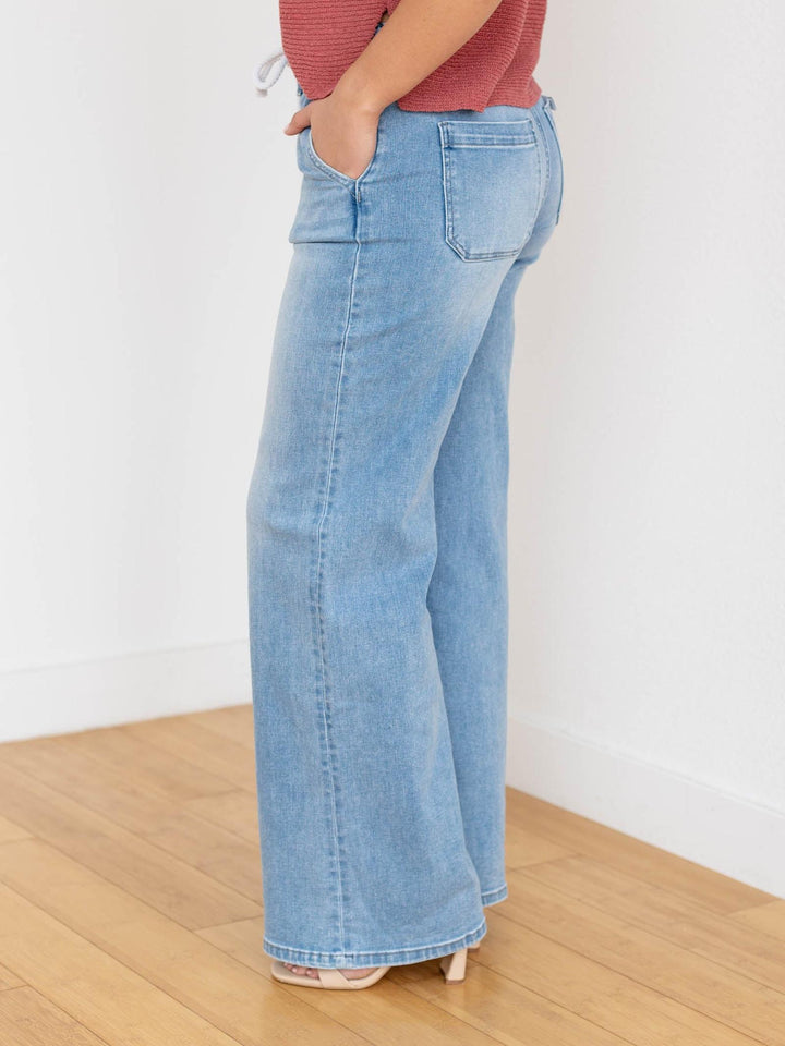 Woman wearing a rust-colored top and light blue jeans on a white background