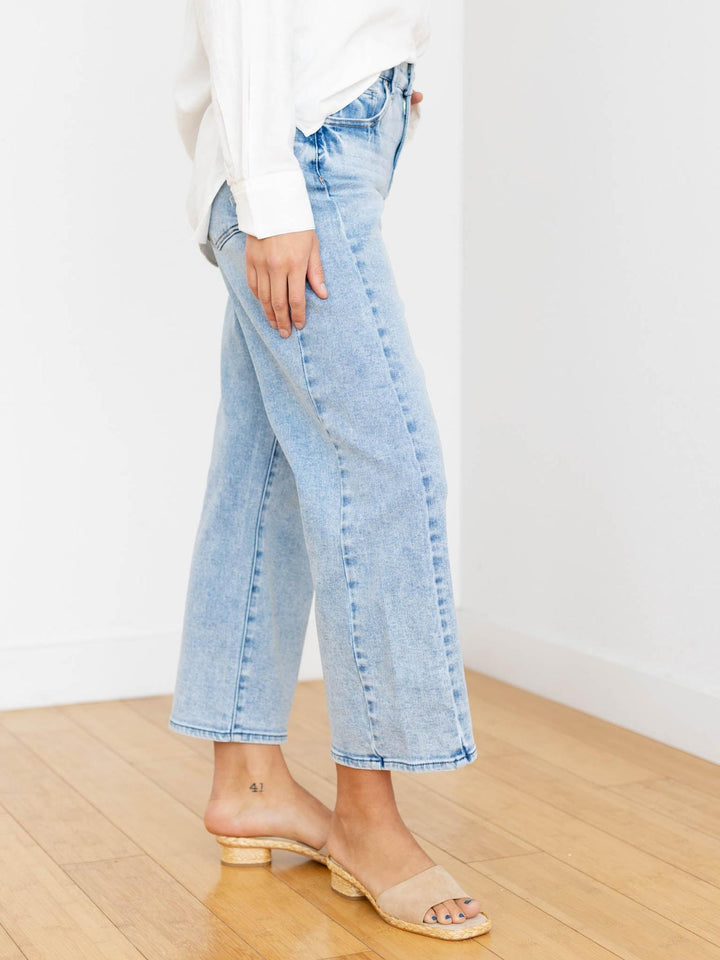 Light blue jeans worn by a person on a wooden floor with a white background