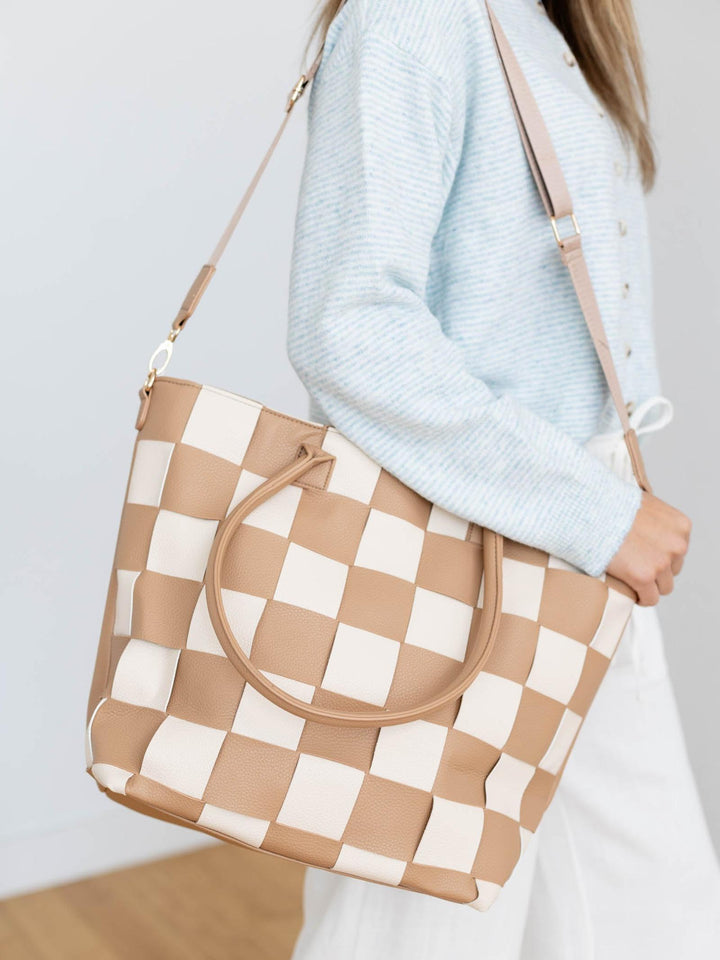 Person holding a checkered handbag with a plain background