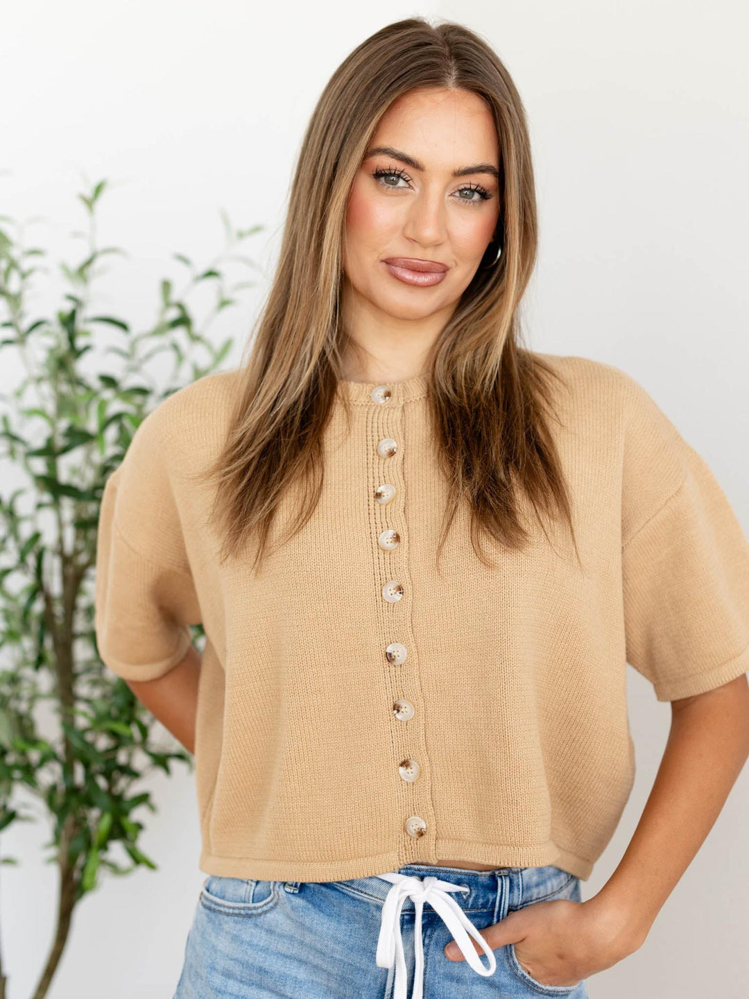 Woman wearing a beige knit cardigan with a white background
