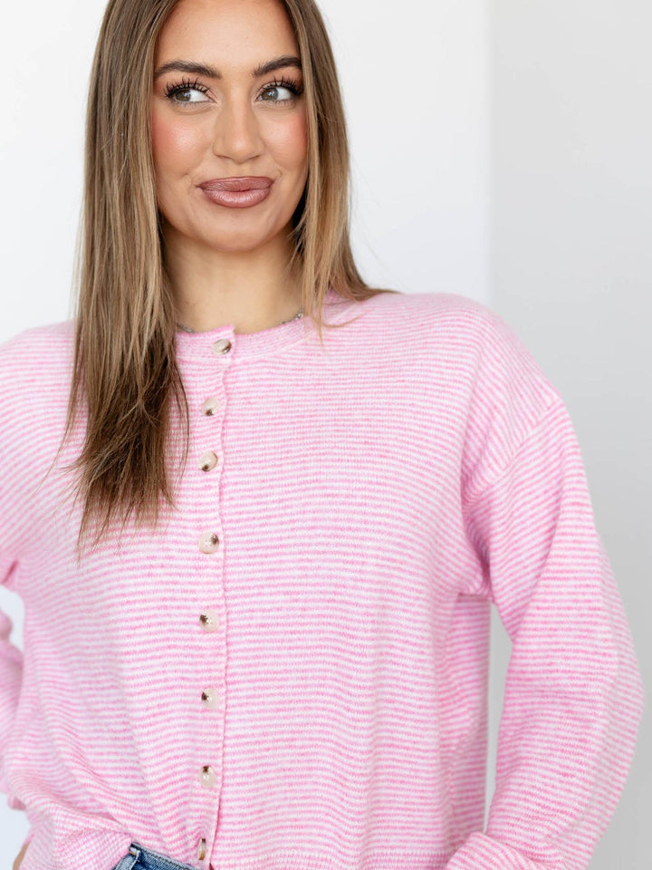 Woman wearing a pink striped shirt against a plain background