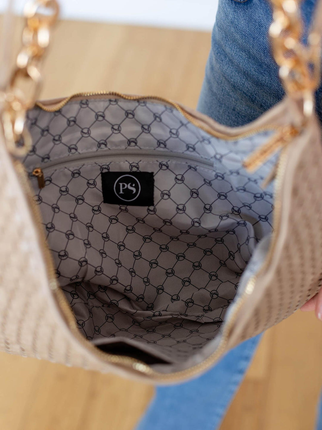 Close-up of a beige handbag with a patterned interior and visible brand logo.