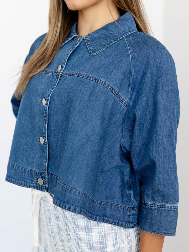Blue denim jacket worn by a person on a plain background