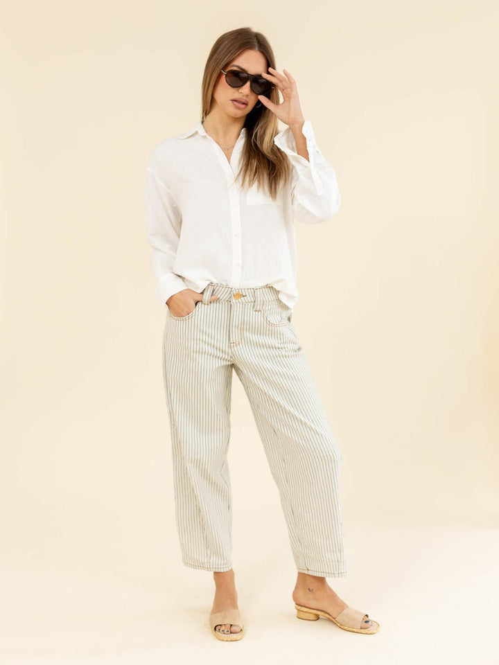 Woman wearing a white shirt and striped pants on a beige background