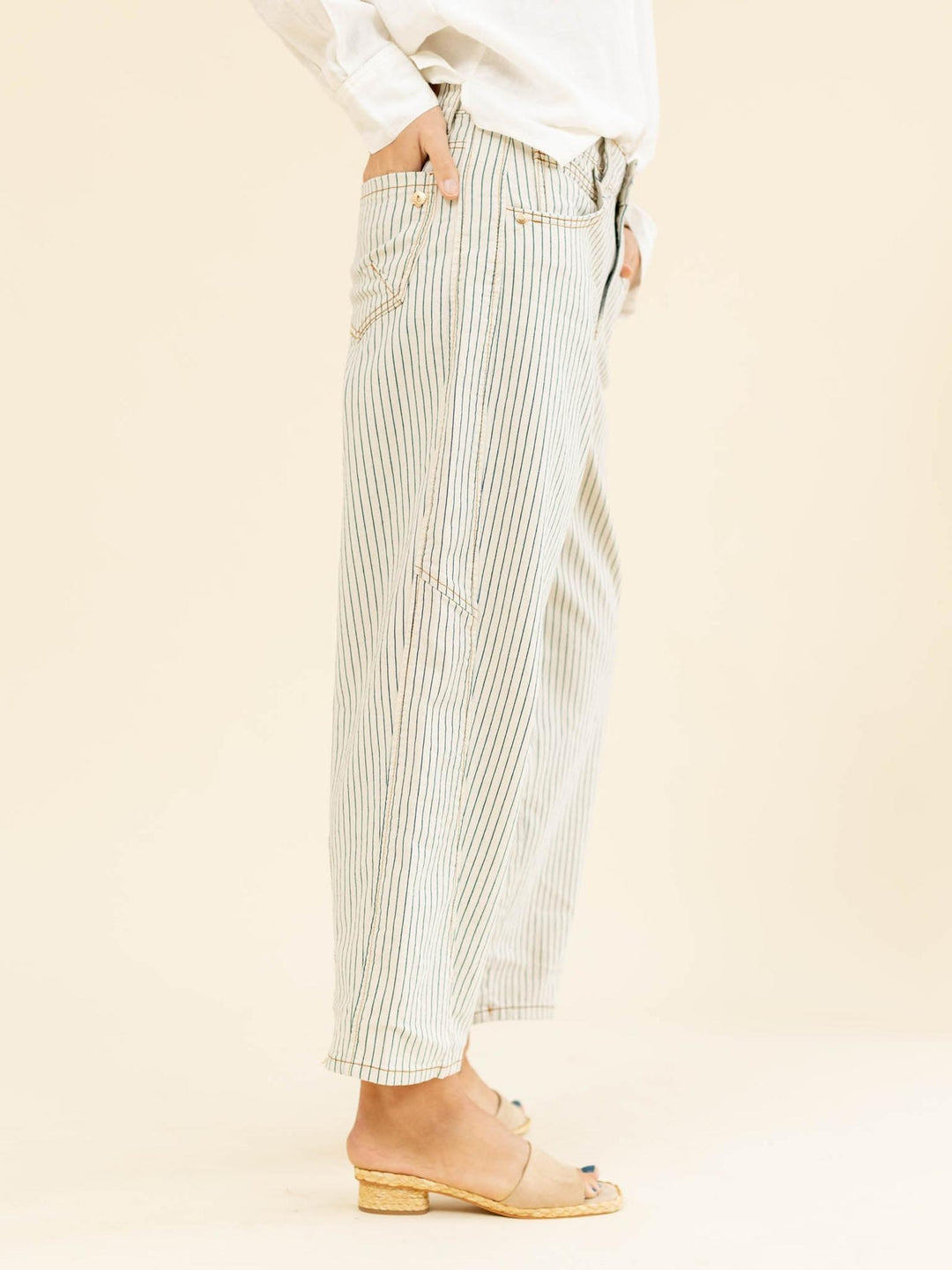 Person wearing light-colored striped pants on a beige background