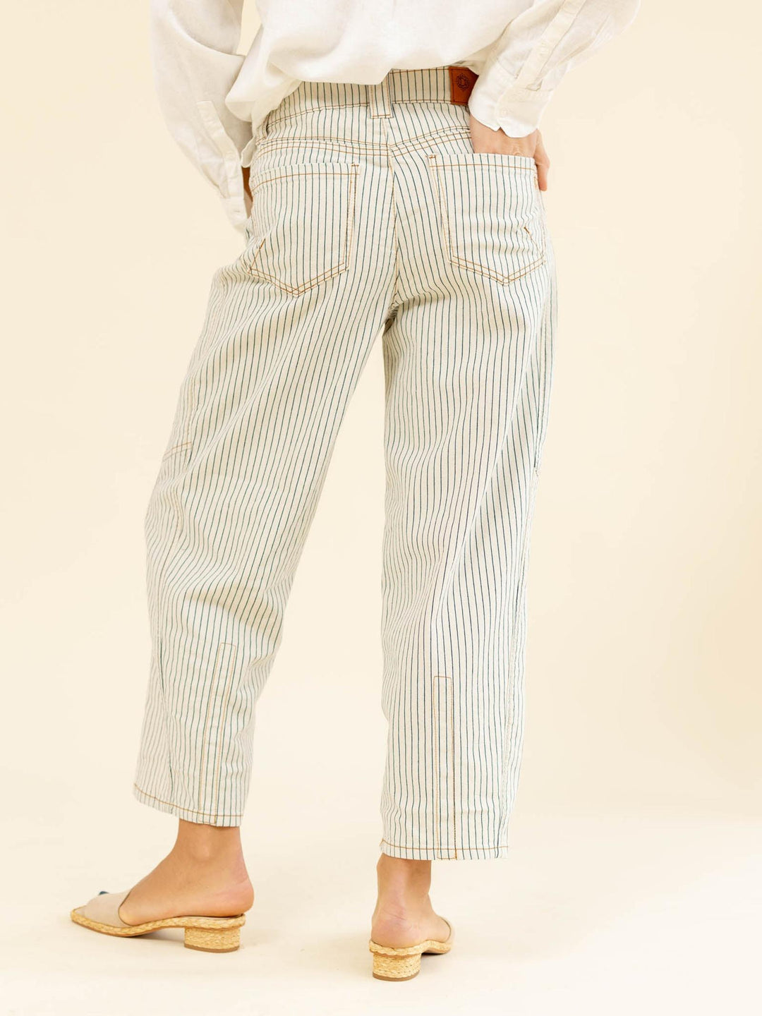 Person wearing light-colored striped pants on a beige background
