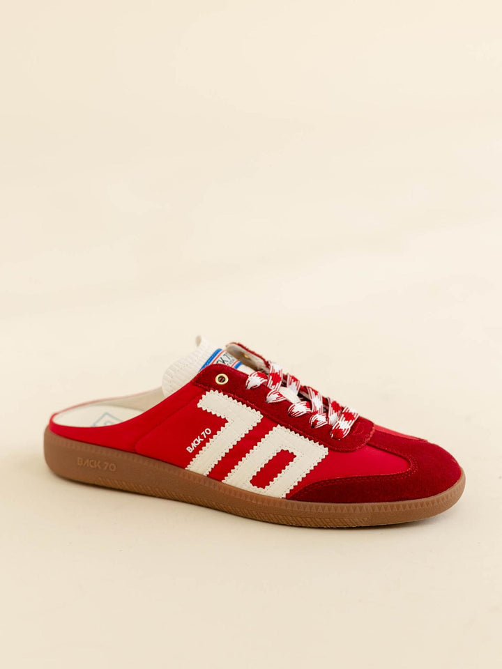Red sneaker with white stripes on a beige background