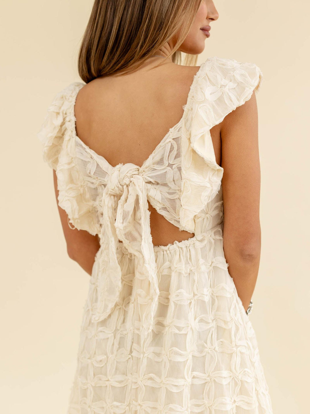 White lace dress with cut-out back on a beige background