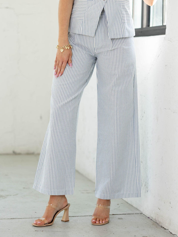 Person wearing a striped suit with wide-leg pants in a minimal indoor setting.