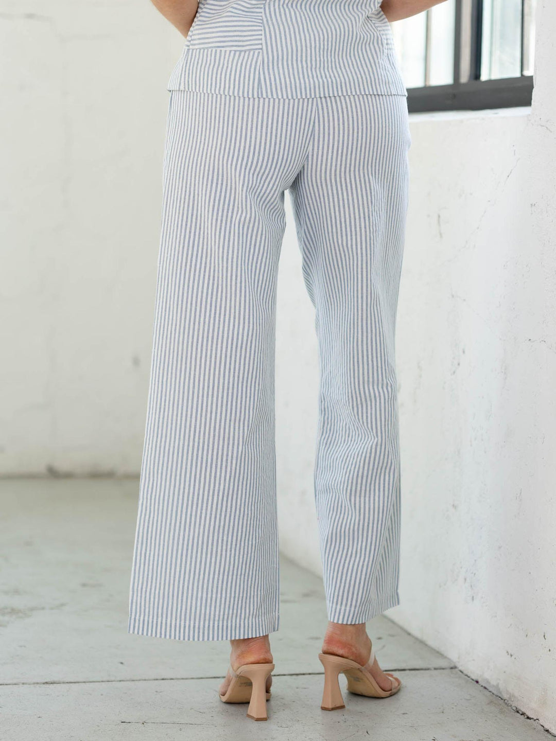 Person wearing blue and white striped pants in a minimal indoor setting