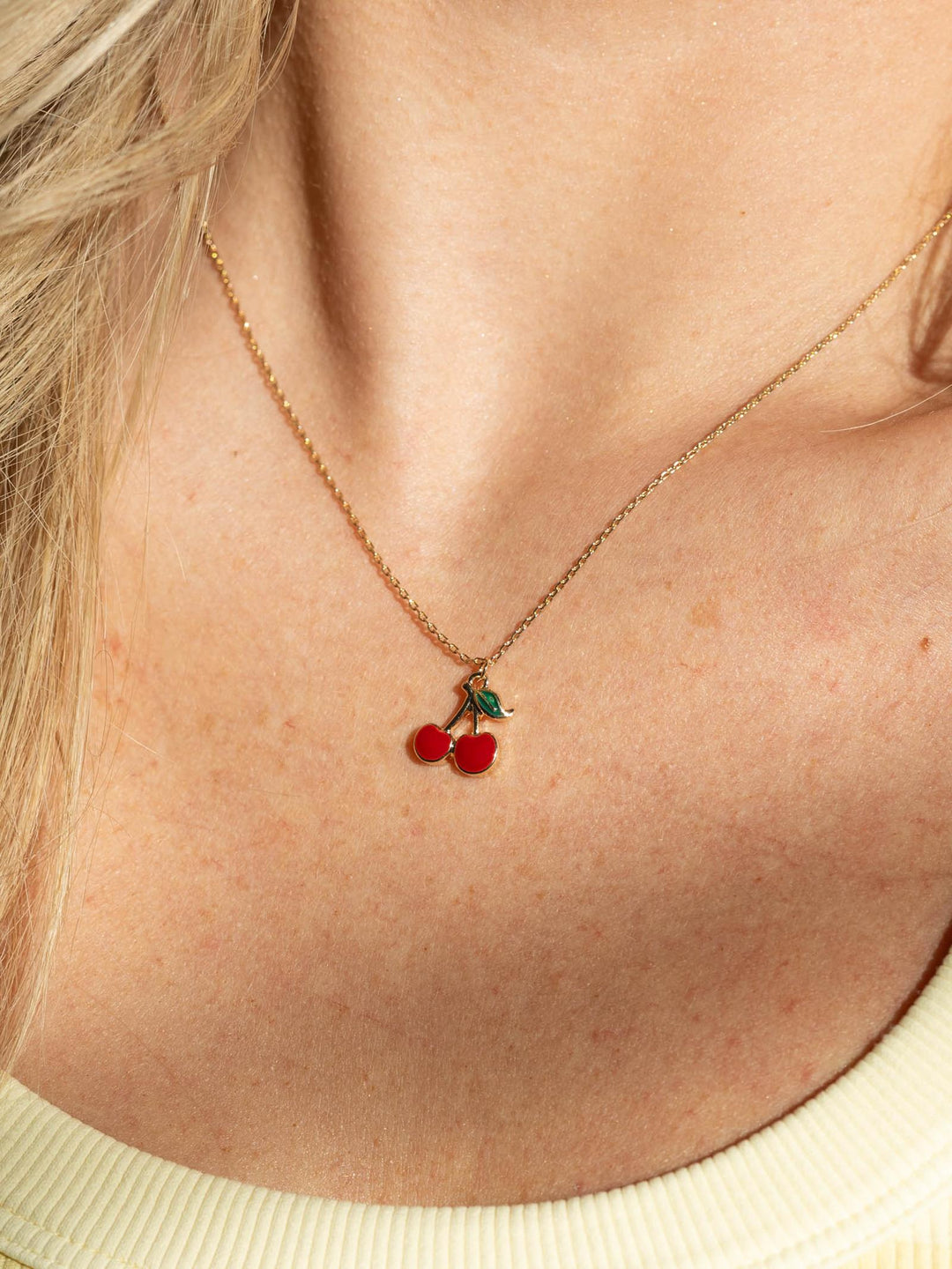 Necklace with cherry pendant worn by a person