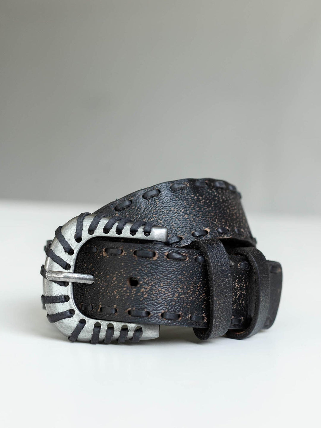 Free People Holt black distressed leather belt with a silver Western-inspired metal buckle and stitch detailing.