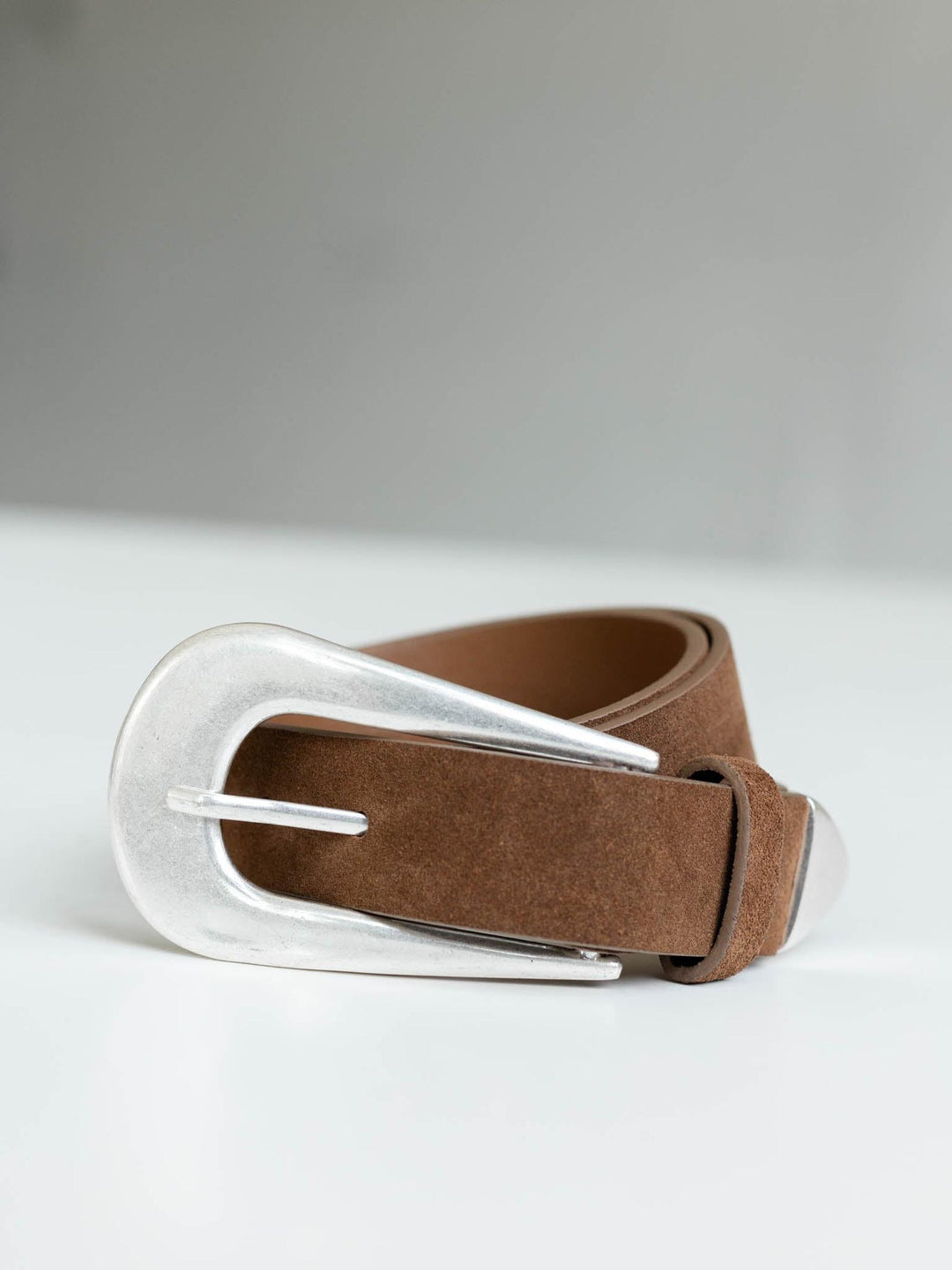 Free People Cannon Suede Belt in brown with a large, rounded silver metal buckle.