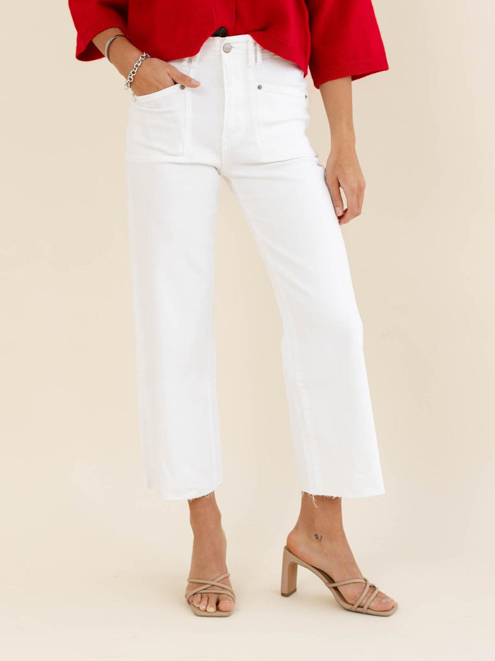 Person wearing a red top and white jeans on a beige background