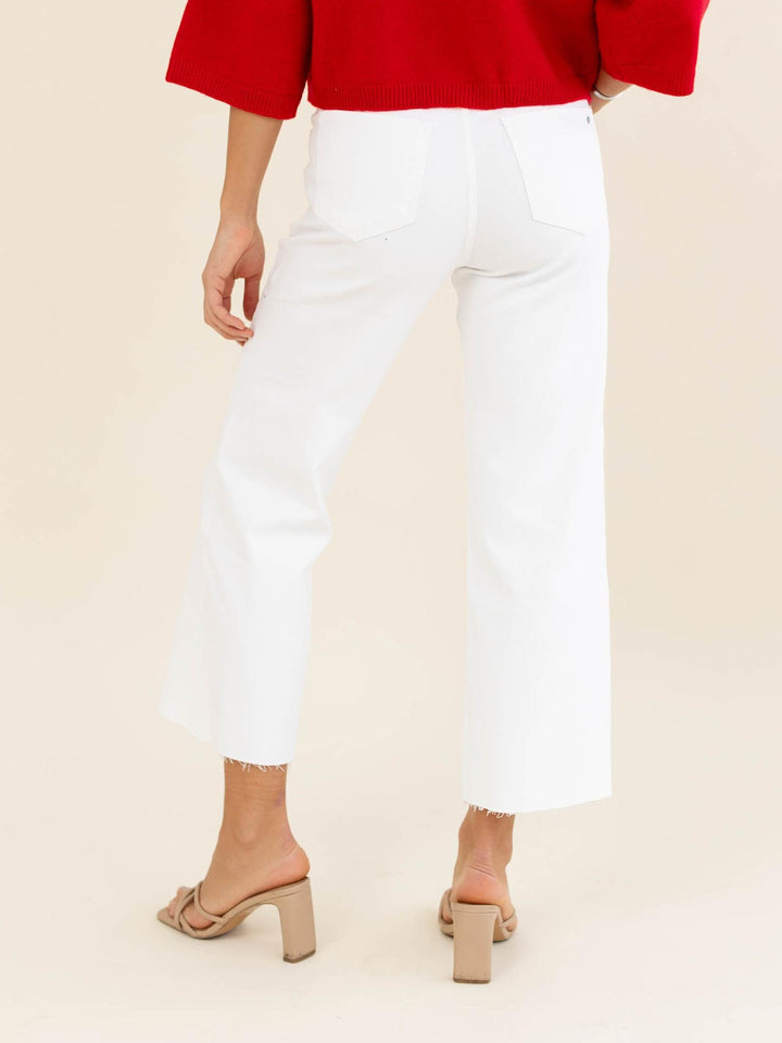 Person wearing a red top and white pants on a beige background