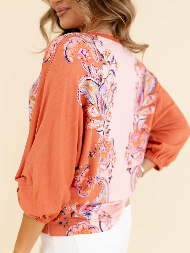 Woman wearing a colorful patterned top with a neutral background